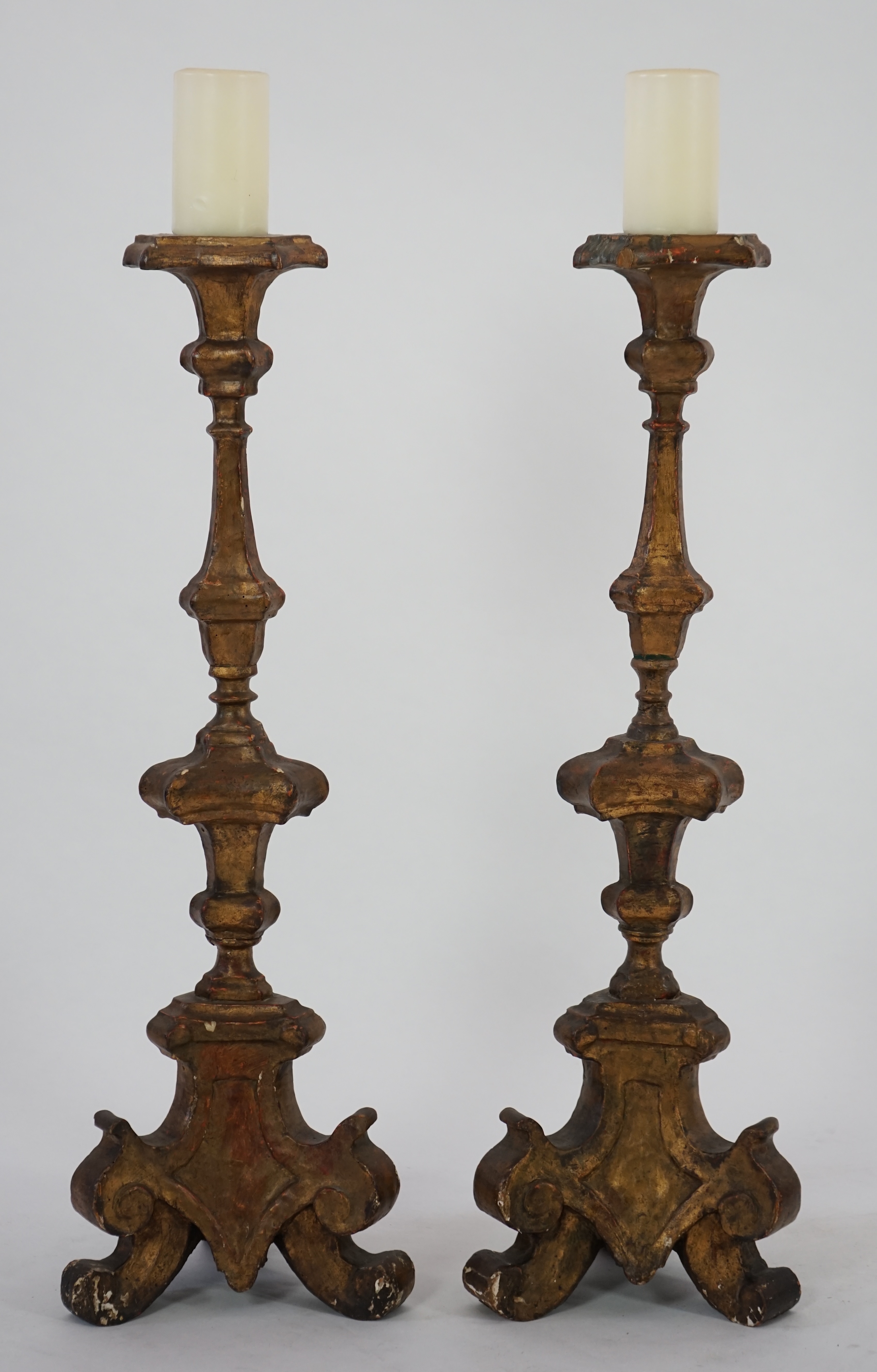 A pair of 18th century Italian giltwood candlesticks with knopped triangular stems and scroll feet, 89cm high. Condition - fair, Provenance- Brede Place, East Sussex, a former residence of the Frewen family from 1712-193
